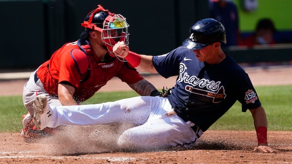 Atlanta Braves' Jake Lamb slides past Boston Red Sox catcher Christian Vazquez to score on a Cristian Pache sacrifice fly in the fifth inning Tuesday, March 23, 2021, at CoolToday Park in North Port, Fla. (John Bazemore/AP)