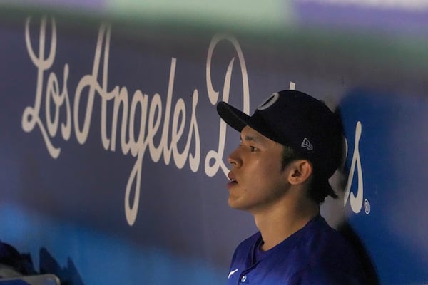 Los Angeles Dodgers pitcher Roki Sasaki (11) rests in the dugout between the fifth and sixth inning of a spring training baseball game against the Cincinnati Reds, Tuesday, March. 4, 2025, in Phoenix. (AP Photo/Darryl Webb)