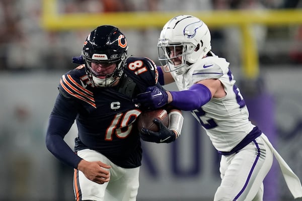 Chicago Bears quarterback Caleb Williams runs from Minnesota Vikings safety Harrison Smith, right, during the first half of an NFL football game, Monday, Dec. 16, 2024, in Minneapolis. (AP Photo/Abbie Parr)