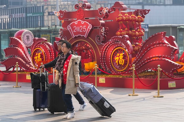 Travelers walk towards the departure hall to catch their trains at the Beijing West Railway Station ahead of the Lunar New Year in Beijing on Friday, Jan. 24, 2025. (AP Photo/Aaron Favila)