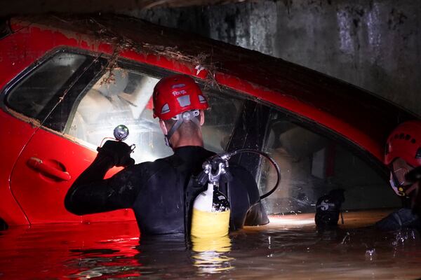 Civil Guards walk in a flooded indoor car park to check cars for bodies after floods in Paiporta, near Valencia, Spain, Monday, Nov. 4, 2024. (AP Photo/Alberto Saiz)