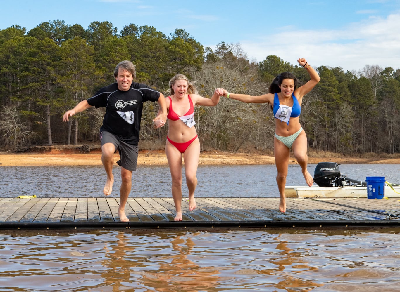 Drew Merrill, from left, Lola Merrill and Camila Montes participate in the 26th annual Polar Bear Paddle and Plunge at Lake Lanier Olympic Park on Monday, Jan 1, 2024.   (Jenni Girtman for The Atlanta Journal-Constitution)