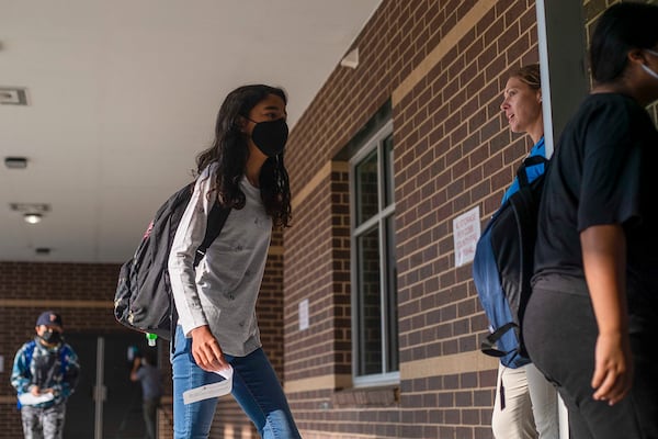 Physical Education Coach Monica Sicka greets a few masked students as they enter Pearson Middle School during the first day of school in Marietta, Monday, August 2, 2021. (Alyssa Pointer/Atlanta Journal Constitution)