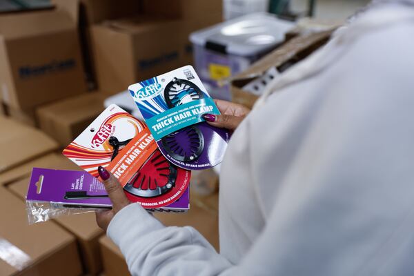 Ceata Lash, founder and owner of PuffCuff, holds the different products she sells online and in stores at her warehouse in Marietta on Tuesday, Feb. 20, 2024. The company makes specialized clasps for people with curly hair. (Natrice Miller/ Natrice.miller@ajc.com)