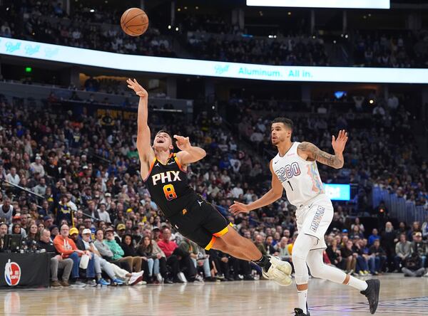 Phoenix Suns guard Grayson Allen, left, flies in the air after being fouled by Denver Nuggets forward Michael Porter Jr. in the second half of an NBA basketball game Friday, March 7, 2025, in Denver. (AP Photo/David Zalubowski)