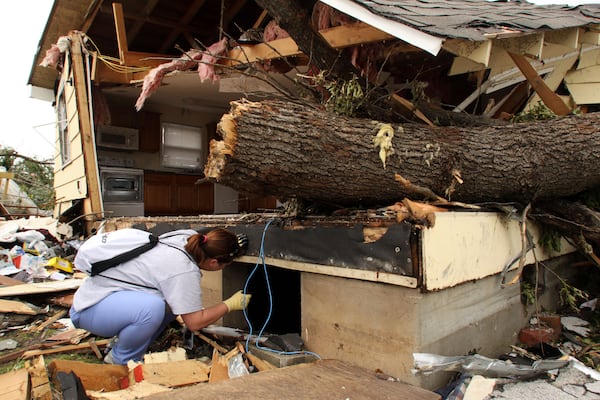 FILE- Nurse Danielle Sipi of Jefferson City, Mo., shines a flashlight into the crawlspace of a home in Duquesne, Mo., Wednesday, May 25, 2011, as part of a line search for overlooked storm victims. (AP Photo/Mark Schiefelbein, File)