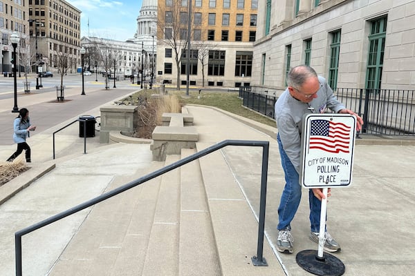 Volunteer Wade DallaGrana puts out a sign ahead of the start of early voting in the Wisconsin Supreme Court race on Tuesday, March 18, 2025, in Madison, Wisconsin. (AP Photo/Scott Bauer)