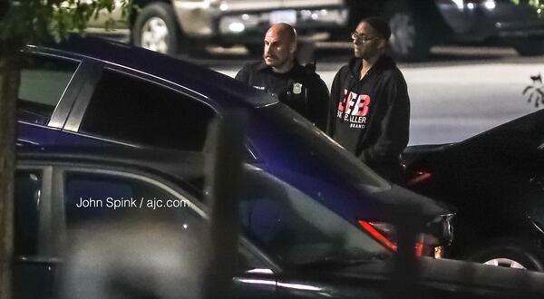 Morehouse College student Deaven Rector, 19, stands with an Atlanta police officer as authorities tow away his Toyota Corolla for processing. Rector’s car was stolen from him in southwest Atlanta Tuesday morning and later recovered.