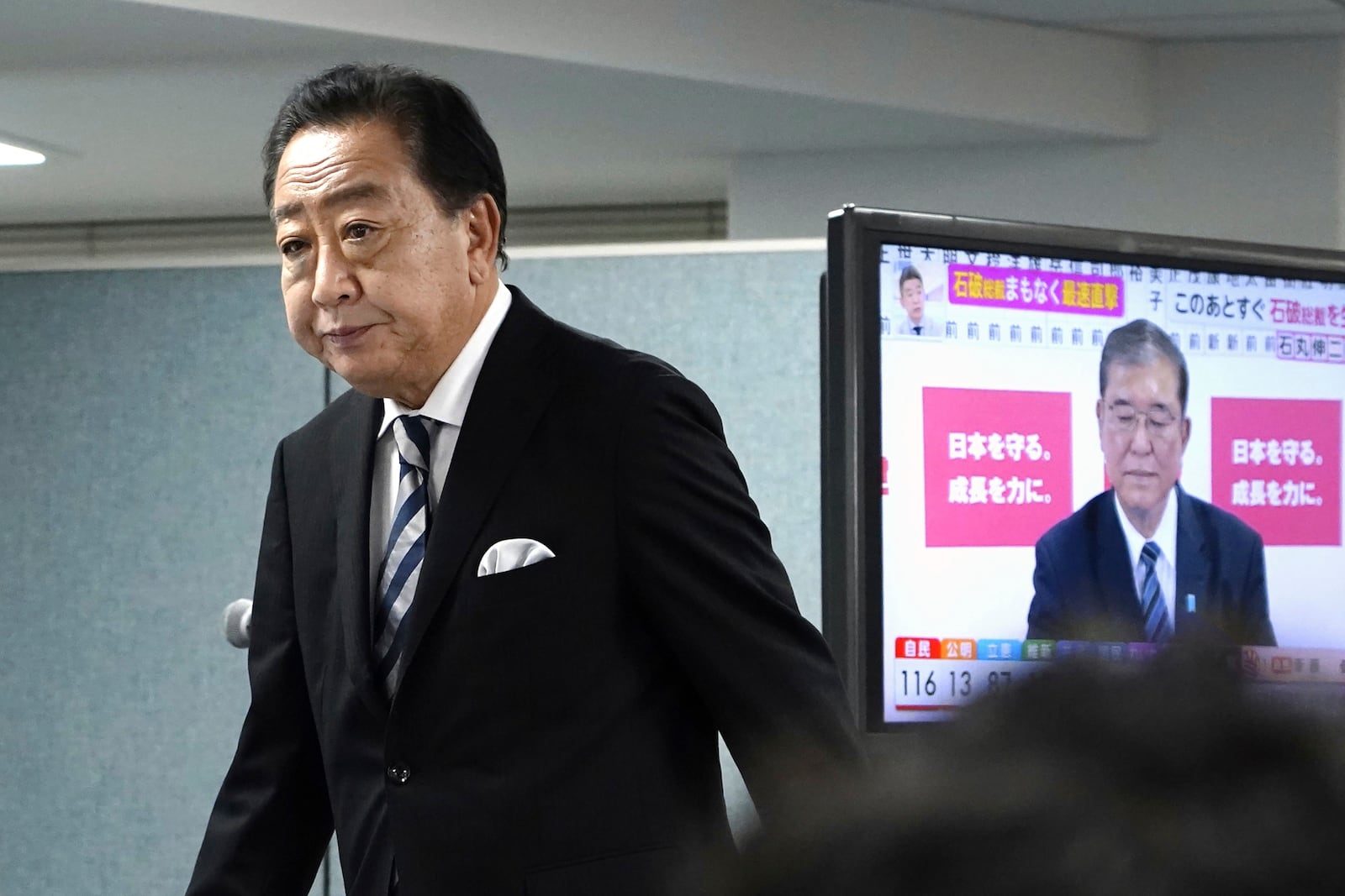 Yoshihiko Noda, leader of Japan's opposition Constitutional Democratic Party, prepares for a media interview with Japan's Prime Minister and president of the Liberal Democratic Party (LDP) Shigeru Ishiba seen on TV screen, at Noda’s party headquarters Sunday, Oct. 27, 2024 in Tokyo, (Kyodo News via AP)