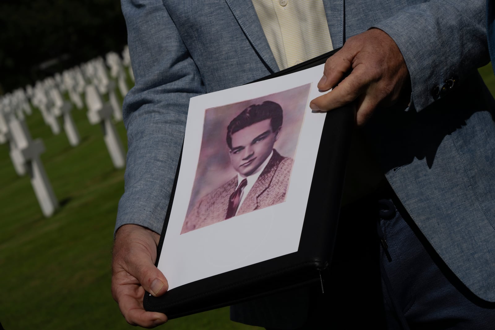 Eighty years after the liberation of the south of the Netherlands Ton Hermes holds a picture of Second Lt. Royce Taylor, a bombardier with the 527 Bomb Squadron, next to his grave at the Netherlands American Cemetery in Margraten, southern Netherlands, on Wednesday, Sept. 11, 2024. (AP Photo/Peter Dejong)