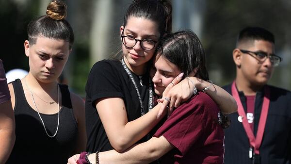 PARKLAND, FLORIDA -- Bella Montecino, who left Marjory Stoneman Douglas High School after the shooting, and Makenzie Henser (L-R), who is a junior at Marjory Stoneman Douglas High School, comfort each other as they remember those lost during a mass shooting at the school on February 14, 2019 in Parkland, Florida. A year ago on Feb. 14th at Marjory Stoneman Douglas High School 14 students and three staff members were killed during the mass shooting.  