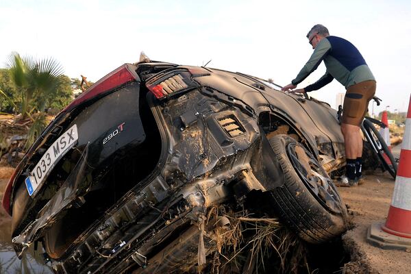 Jorge Tarazona attaches a poster to a car in Paiporta, Valencia, Spain, Wednesday, Nov. 5, 2024, where his three-year-old niece and sister-in-law died in last week's floods in eastern Spain. (AP Photo/Paolo Santalucia)