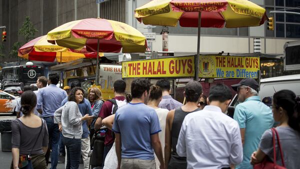 Customers stand in line at The Halal Guys' food cart in New York, U.S., on Sept. 9, 2016. MUST CREDIT: Bloomberg photo by Michael Nagle.