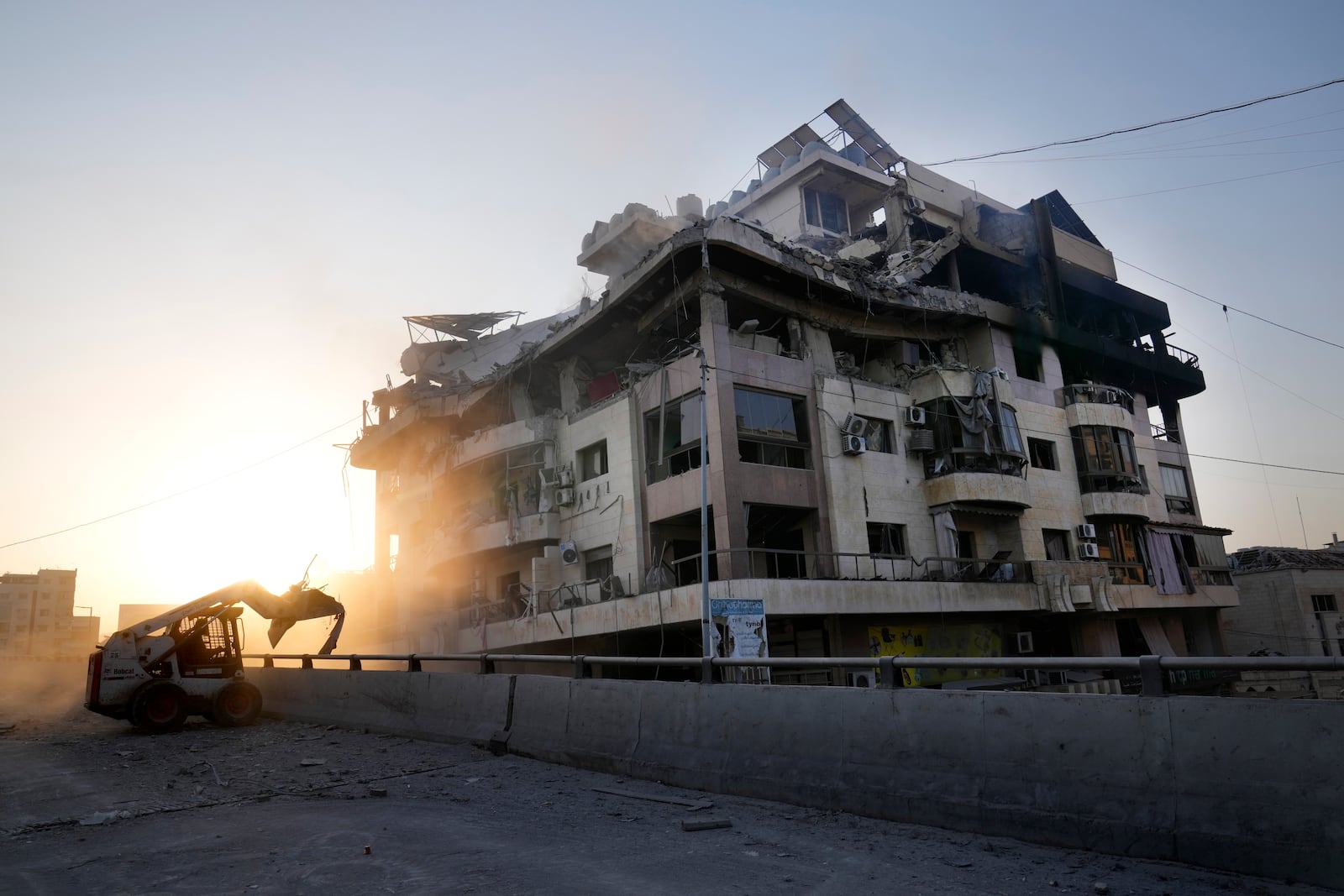 A municipality worker uses a skid steer loader to reopen a bridge closed by the rubble of a destroyed building that was hit by an Israeli airstrike on Dahiyeh, in the southern suburb of Beirut, Lebanon, Friday, Nov. 1, 2024. (AP Photo/Hussein Malla)