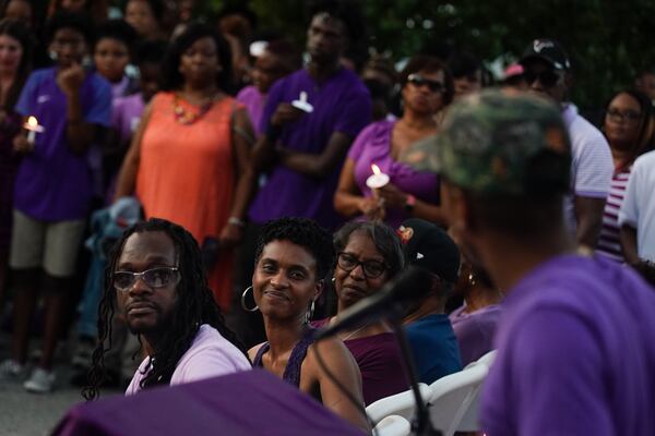 Imani Bell's parents look on as the teen's former coach speaks during Wednesday candlelight vigil.