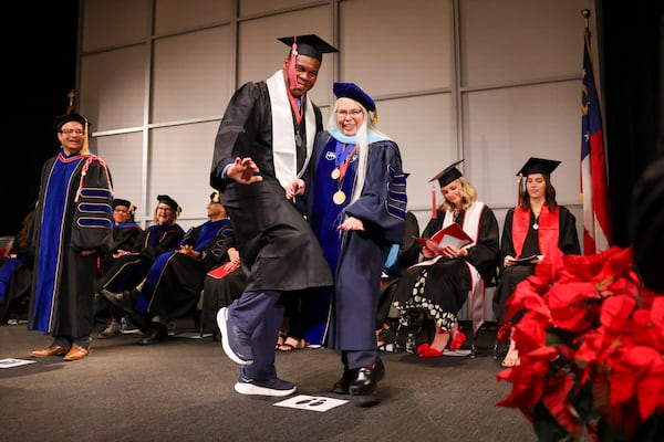 1982 Heisman Trophy winner and former Georgia running back Herschel Walker strikes the heisman pose with Anisa Zvonkovic, the dean of the University of Georgia’s College of Family and Consumer Sciences, during the college’s fall graduation ceremony, Thursday, December 12, 2024, in Athens, Ga. (Jason Getz / AJC)
