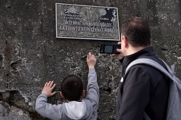 Visitors take pictures of the United States-Canada border marker on the Point Roberts Maple Beach, Saturday, March 1, 2025, in Point Roberts, Wash. (AP Photo/Ryan Sun)