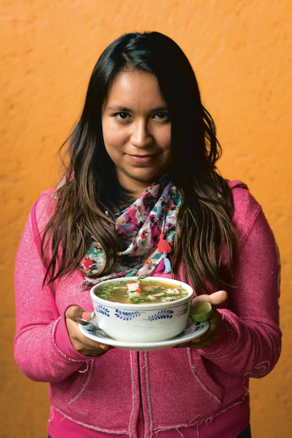 A young woman holds caldo de pollo, Mexico City’s answer to chicken in a pot. Courtesy of Ten Speed Press/James Roper © 2020