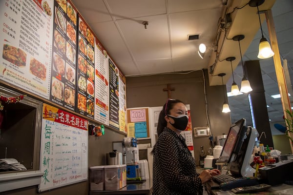 Guijie Zhang, owner of China Kitchen, a small food booth located inside the Atlanta Chinatown Shopping Mall food court, wears two face masks while talking about the changes she has seen take place since the COVID-19 pandemic impacted her way of life in Chamblee, Friday, July 31, 2020. Zhang has installed a clear barrier between herself and her customers near the register for protection against the transmission of germs. (ALYSSA POINTER / ALYSSA.POINTER@AJC.COM)