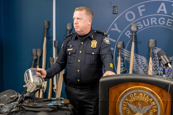 Atlanta Police Chief Darin Schierbaum, holding a gas mask retrieved from a demonstration, speaks at a press conference in Atlanta on Monday, November 13, 2023, following a clash between police and demonstrators protesting against Atlanta’s public safety training center. Police characterized the tools (background) carried by demonstrators, some of whom used them to plant trees, as potential weapons. (Arvin Temkar / arvin.temkar@ajc.com)