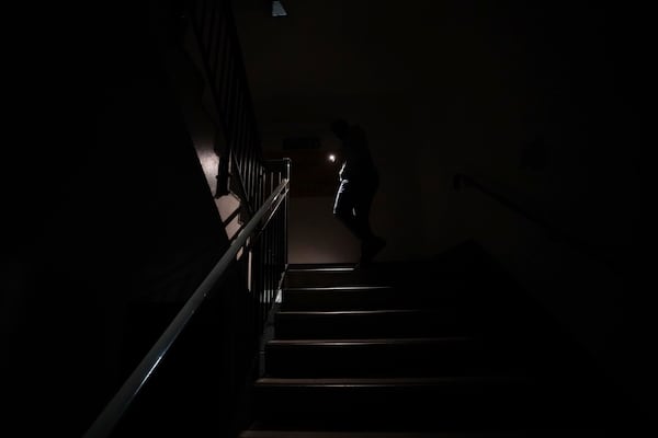 Stranded passengers makes their way down unlit stairs due to lifts not working to the car park at Heathrow Terminal 4 in London, Friday March 21, 2025, as consequence of the closure of the airport following a fire at the North Hyde electrical substation last night. (James Manning/PA via AP)