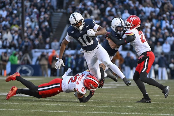 Penn State running back Nicholas Singleton (10) hurdles Maryland defensive back Dante Trader Jr. (12) during the first quarter of an NCAA college football game, Saturday, Nov. 30, 2024, in State College, Pa. (AP Photo/Barry Reeger)