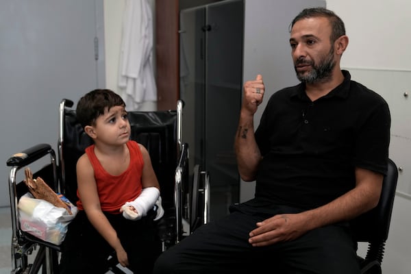 Hussein Mikdad, 4, left, who was injured on Oct. 2 in an Israeli airstrike at a densely-populated neighborhood south of Beirut, looks at his father Hassan, during an interview with The Associated Press at the American University of Beirut Medical Center (AUBMC), in Beirut, Lebanon, Tuesday, Nov. 5, 2024. (AP Photo/Bilal Hussein)