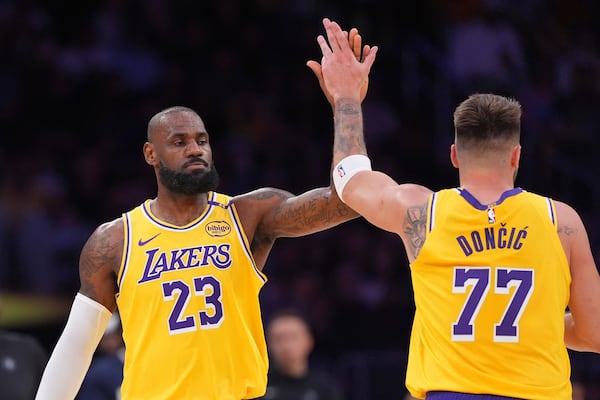 Los Angeles Lakers forward LeBron James, left, is congratulated by guard Luka Doncic after he scored during the first half of an NBA basketball game against the Minnesota Timberwolves, Thursday, Feb. 27, 2025, in Los Angeles. (AP Photo/Mark J. Terrill)