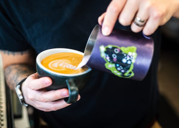 Postern Coffee co-founder Joshua Owh makes a hot coconut ube latte at the company's Doraville coffee shop. He shared the recipe for the syrup to make the popular flavored drink at home. (Henri Hollis / AJC)