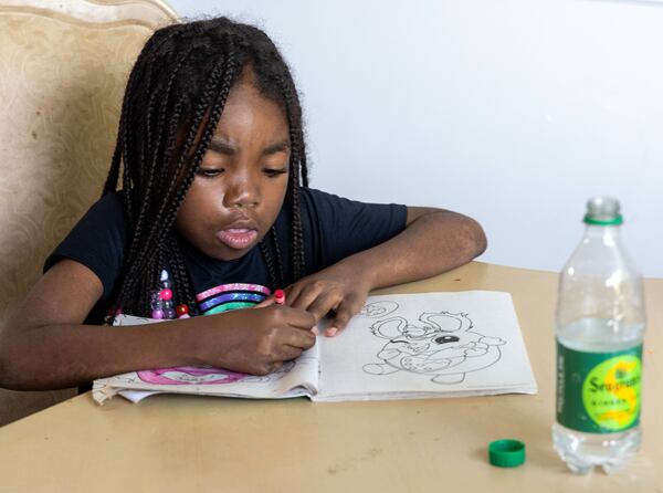 J'Adore Sledge colors as her mother Ebon Sledge helps her siblings with their homework in their new rental home in metro Atlanta.  PHIL SKINNER FOR THE ATLANTA JOURNAL-CONSTITUTION