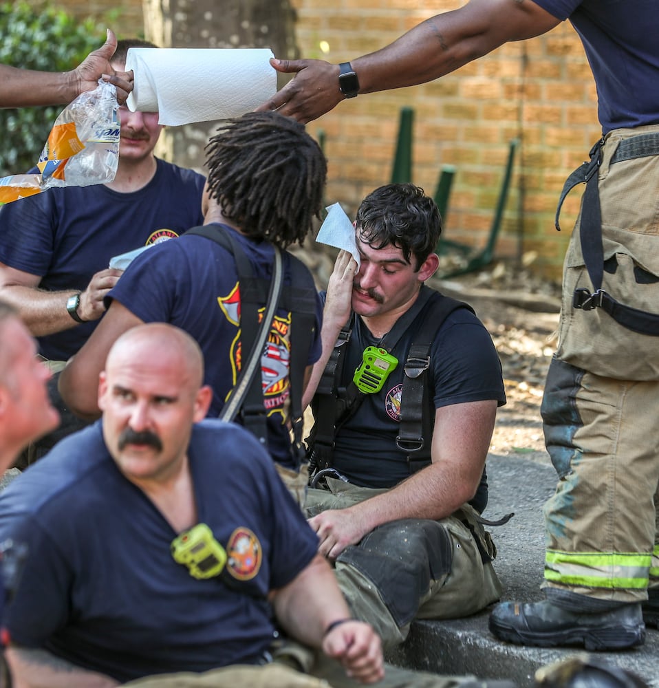 July 7, 2022 Atlanta: Atlanta firefighter, Gavin Lamb of Engine 9 wipes the sweat as Atlanta firefighters had a hot morning battling an apartment blaze in the 2200 block of Campbellton Road in Atlanta on Thursday, July 7, 2022. The call came in at 9 am for the Adams House Apartments where units arrived to heavy smoke conditions according to Atlanta Fire Rescue Captain Taurus Durrah. Flames erupted from the bottom floor to the top floor and then the attic Durrah said. Crews initially had to bring in tank water to get water on the fire because of the 800 foot distance to the hydrant on Campbellton Road. Four units were damaged and 8-families displaced. No one was injured and the fire is under investigation. Durrah said more units are being sent to fire scene to shorten the rotation of fire crews due to the heat. Firefighters are told to hydrate  and stay cool a full shift before coming to work to combat the heat. (John Spink / John.Spink@ajc.com)


