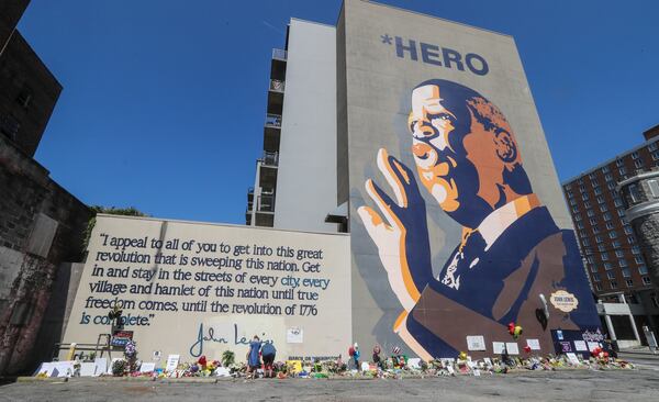 Amanda Hiley and her husband Todd Heifner place flowers and a candle at the John Lewis mural.