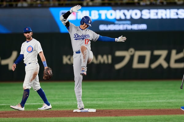 The Dodgers' Shohei Ohtani celebrates a ninth-inning double during the MLB Japan Series opener in Tokyo, as Cubs shortstop Dansby Swanson looks on.