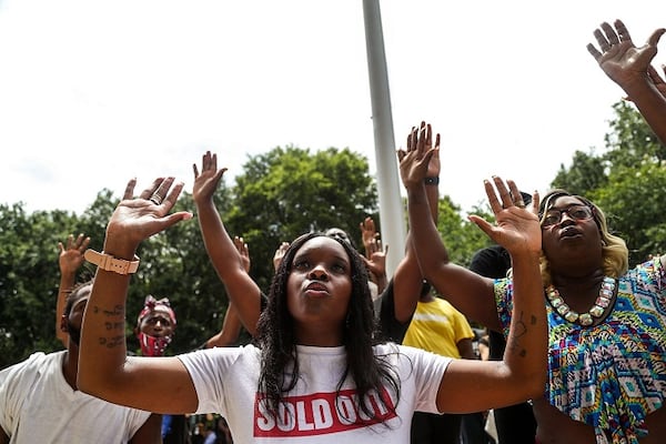 Kaisha Givens, center, 33, kneels as she and others chant “Hands up, Don’t shoot” outside of the Glynn County Courthouse.