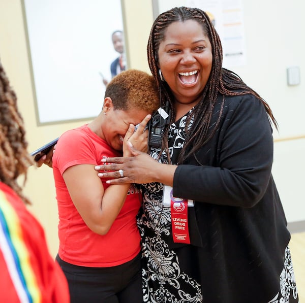 Dance instructor Lisa Perrymond, left, gets a hug from Principal Dione Simon Taylor after Taylor stopped by the studio to watch a dance rehearsal.    Bob Andres / robert.andres@ajc.com