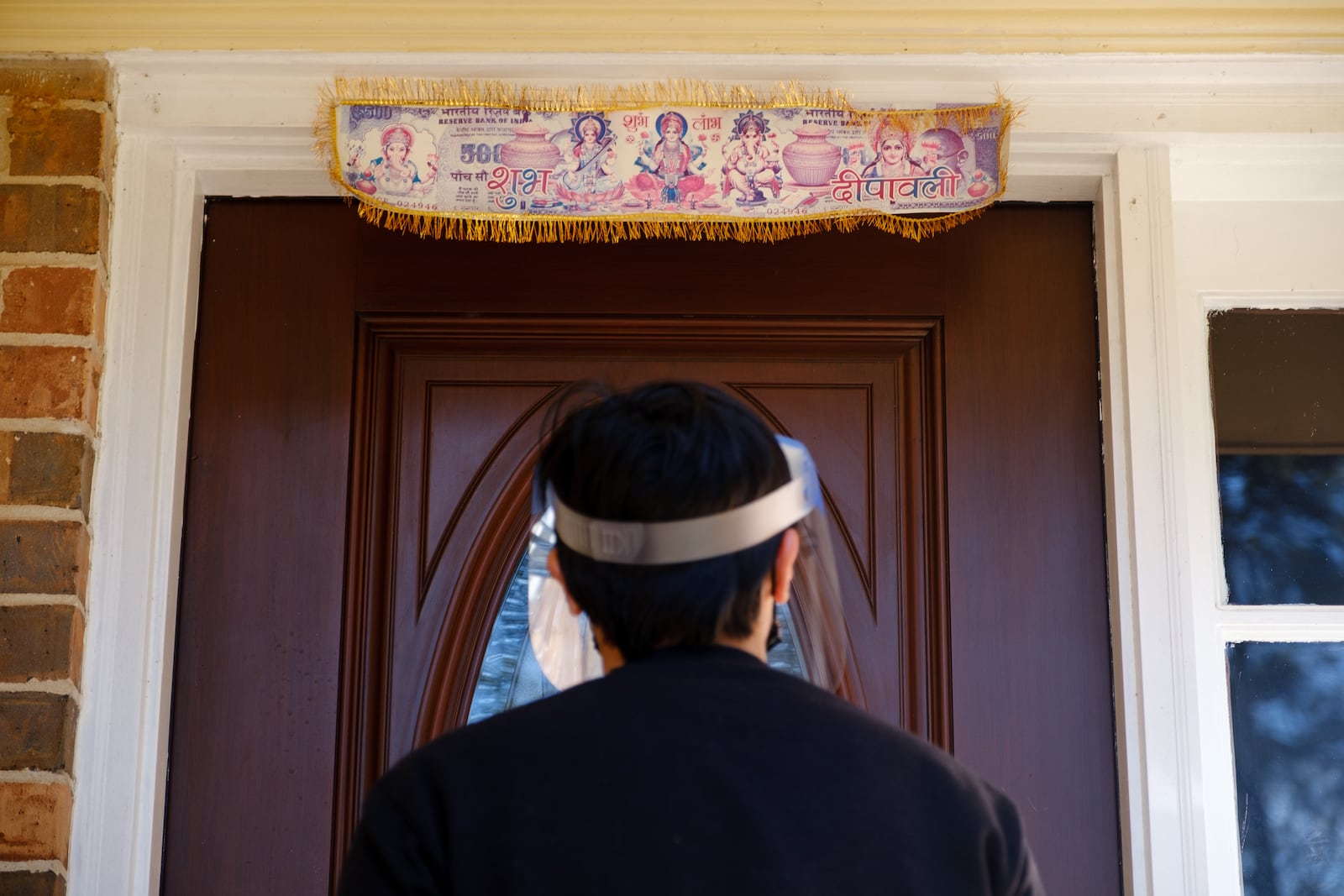 Andy Mai, a field organizer with left-leaning organization Asian American Advocacy Fund, stands in front of a household displaying a sign wishing visitors a "Happy Diwali," while canvassing in Stone Mountain on Saturday, Dec. 19, 2020. Of the state's estimated 620,000 AAPI residents, more than 177,000 identify as Indian American, according to AAPI Data. Diwali is known as the Hindu festival of lights, with variations celebrated by other Indian religious groups. 