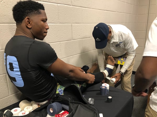 Cedar Grove quarterback E.J. Colson gets his ankle taped before the GHSA Class 3A state championship game against Savannah Christian, Dec. 13, 2023 at Mercedes-Benz Stadium. (Photo by Ken Sugiura/The Atlanta Journal-Constitution)