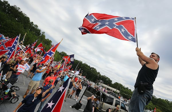 080215 STONE MOUNTAIN: Travis Conklin, Barnesville, waves a flag from the top of his truck durig a pro-Confederate flag rally at Stone Mountain Park on Saturday, August 1, 2015, in Stone Mountain. Curtis Compton / ccompton@ajc.com