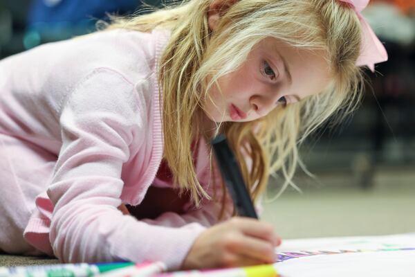 First grade student Hobbs Lindsey colors a poster showcasing her vote for flowers over trees on Election Day, one of the many "school break play days" at the Alliance Theatre. (Jason Getz / Jason.Getz@ajc.com)