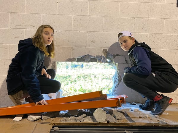 Manda Hunt's children, 11-year-old Jayda and 13-year-old Urijah, pose next to the hole in the wall of the Empty Stocking Fund's warehouse.