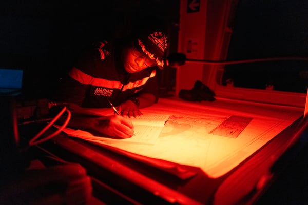 A Senegalese sailor fills in the logbook of the offshore patrol vessel Niani during a mission to search for illegal migrant boats near the coast of Dakar, Senegal, Saturday, Nov.16, 2024. (AP Photo/Sylvain Cherkaoui)