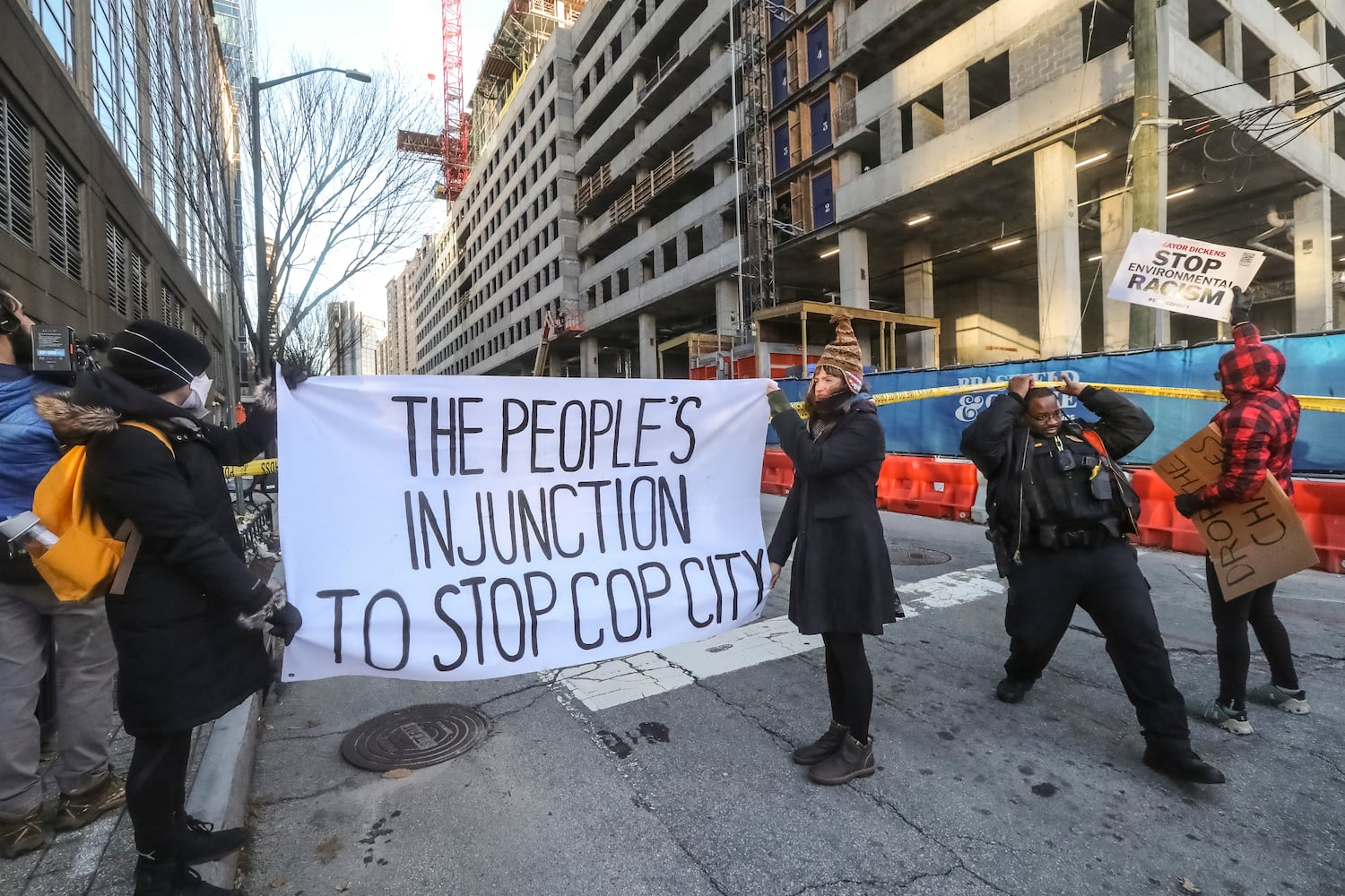 Two people locked themselves to construction equipment in Midtown to protest Atlanta’s planned public safety training center, causing a street to close amid the Monday morning commute, Jan. 29, 2024. The activists used reinforced bindings to lock their arms around the equipment at a Brasfield & Gorrie work site at 12th and Juniper streets. One person was locked to a construction elevator and the other to a boom. Both were released by 10:15 a.m. Juniper Street was closed to traffic for hours Monday morning before reopening around 11:30 a.m. SWAT team members were also at the scene for assistance in cutting the activists free. Brasfield & Gorrie is one of the contractors hired to build the training facility at the site of the old Atlanta Prison Farm in the south DeKalb County woods. Those opposed to the facility say its construction will damage the South River Forest and contribute to what they say is the militarization of the police department. (John Spink / John.Spink@ajc.com)

