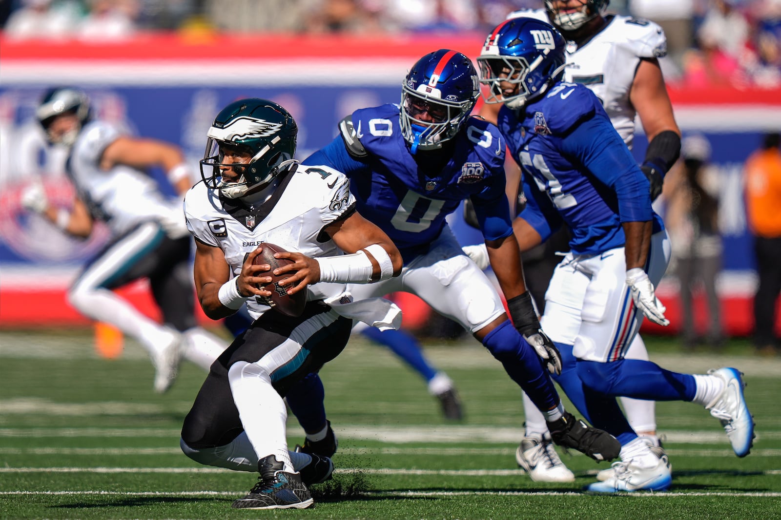 Philadelphia Eagles quarterback Jalen Hurts (1) avoids New York Giants linebacker Brian Burns (0) during the second quarter of an NFL football game, Sunday, Oct. 20, 2024, in East Rutherford, N.J. (AP Photo/Frank Franklin II)