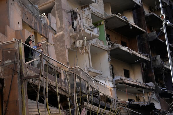 Residents stand on their apartment balcony at a building that was destroyed by an Israeli airstrike in Dahiyeh, in the southern suburb of Beirut, Lebanon, Monday, Nov. 11, 2024. (AP Photo/Hussein Malla)