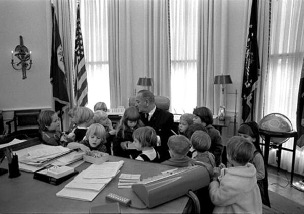 Head Start children surround President Johnson at his desk in the Oval Office. (Head Start)