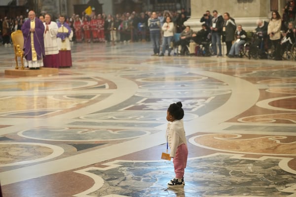 A child follows Vatican Secretary of State, Cardinal Pietro Parolin, left background, delegated by Pope Francis who's being treated for pneumonia at Rome's Agostino Gemelli Polyclinic, presiding over a mass with the pilgrims of the "Movement for Life" in St. Peter's Basilica at The Vatican, Saturday, March 8, 2025. (AP Photo/Gregorio Borgia)