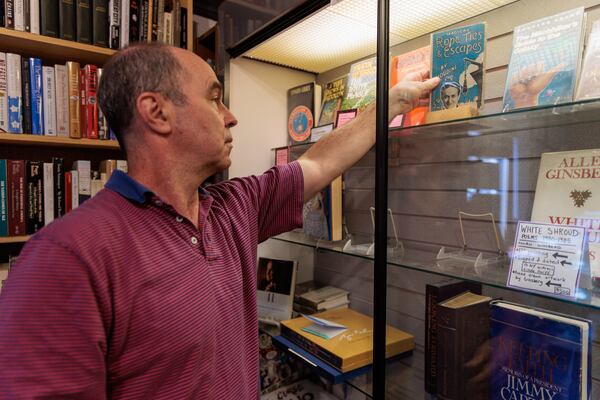 Frank Reiss, owner of A Capella Books in Atlanta, returns books to a display case on Friday, Aug. 5, 2022. (Arvin Temkar / arvin.temkar@ajc.com)