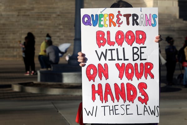 FILE - A protester outside the Kansas Statehouse holds a sign after a rally for transgender rights on the Transgender Day of Visibility, March 31, 2023, in Topeka, Kan. Kansas will no longer change transgender people's birth certificates to reflect their gender identities, the state health department said Friday, Sept. 15, 2023, citing a new law that prevents the state from legally recognizing those identities. (AP Photo/John Hanna, File)