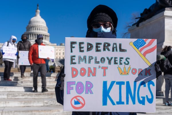 FILE - A federal employee, who asked not to use their name for fears over losing their job, protests with a sign saying "Federal Employees Don't Work for Kings" during the "No Kings Day" protest on Presidents Day in Washington, in support of federal workers and against recent actions by President Donald Trump and Elon Musk, Feb. 17, 2025, by the Capitol in Washington. (AP Photo/Jacquelyn Martin, File)