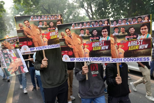 Congress party supporters hold a banners during a protest against Indian billionaire Gautam Adani and Indian Prime Minister Narendra Modi after Adani was indicted by U.S. prosecutors for bribery and fraud, in New Delhi, India, Monday, Nov. 25, 2024. (AP Photo/Manish Swarup)